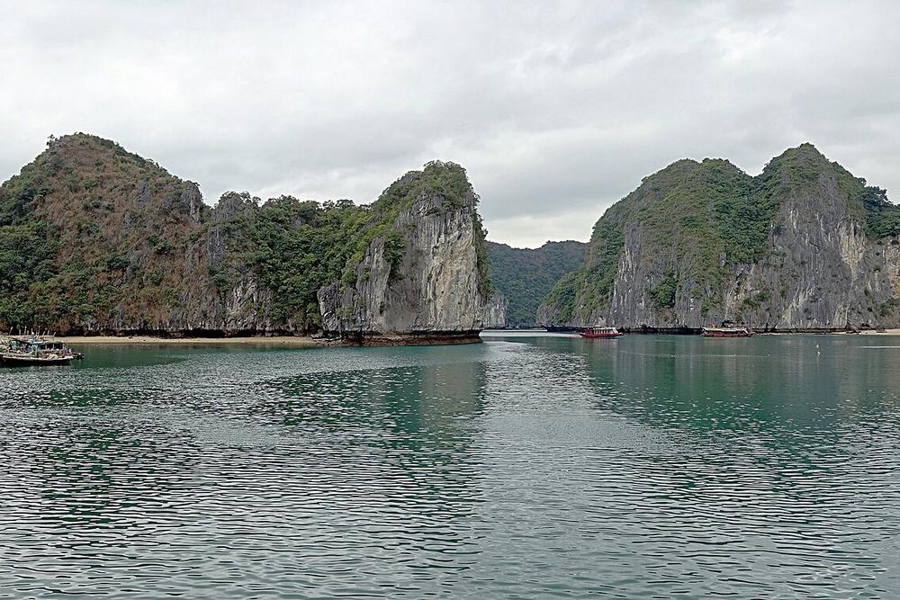 Limestone islands and a wooden boat in Lan Ha Bay at dawn Limestone islands and a wooden boat in Lan Ha Bay at dawn
