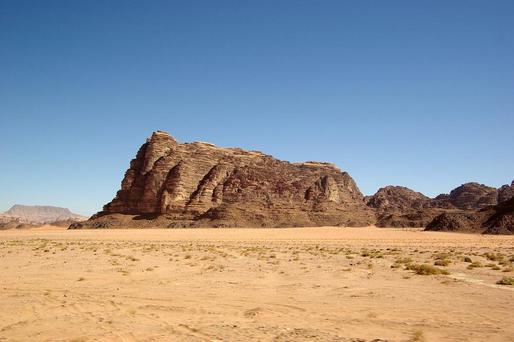 Red sandstone towers rising from sand in Wadi Rum to the south Red sandstone towers rising from sand in Wadi Rum to the south